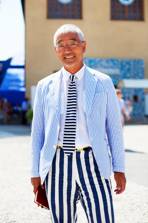 Man wearing a stylish striped suit and tie outdoors.
