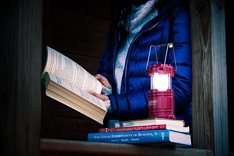 Person reading book by lantern light.