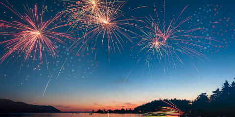 Fireworks over a lake at sunset.