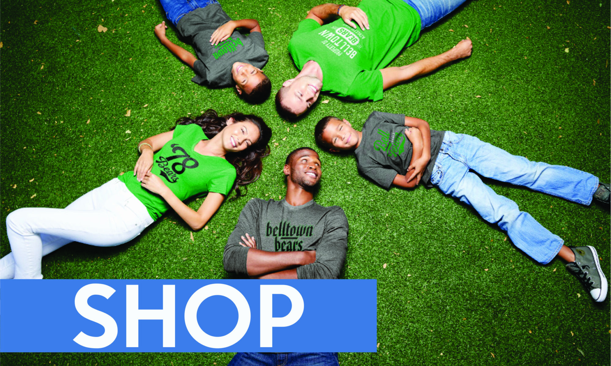 Four friends lying on grass, looking relaxed and happy.
