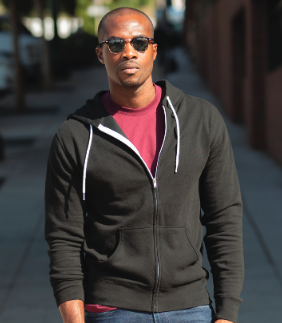Man in sunglasses and hoodie walking outside.