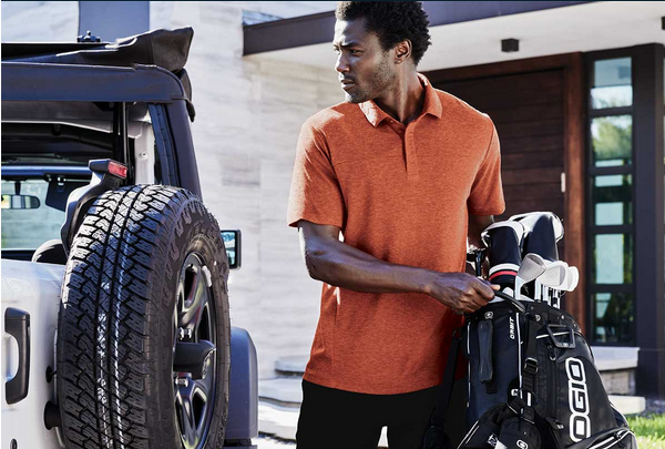 Man holding golf bag beside a jeep.